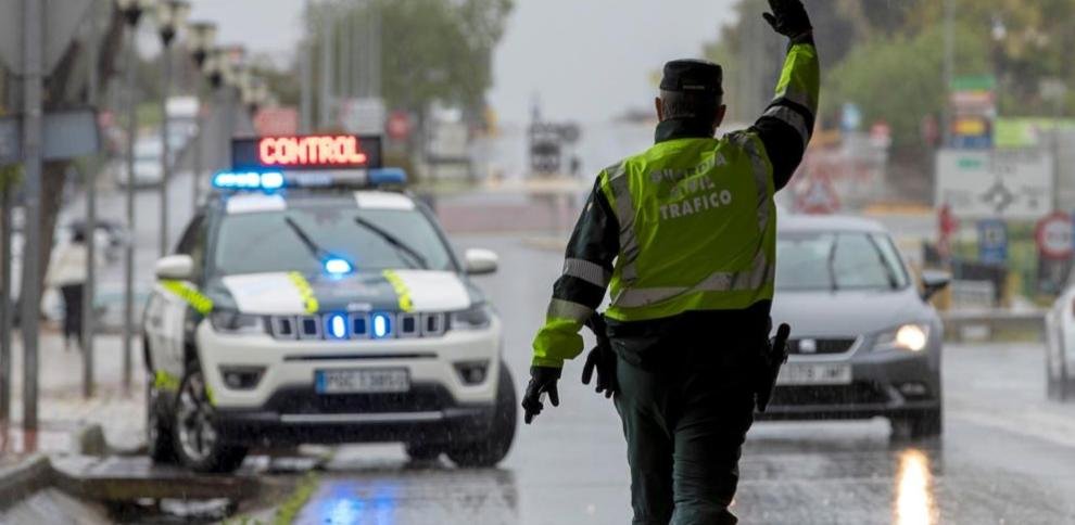 Agente de tráfico dirigiendo el control vehicular bajo la lluvia.